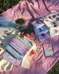 a pink blanket covered in lots of books and other items on top of the ground