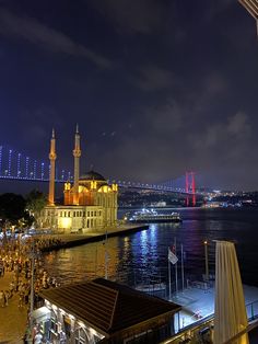 a night view of the city and its bridge from across the water with people walking on it