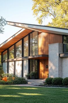 a modern house with large windows and wood sidings on the roof, surrounded by green grass