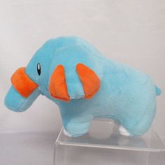 a blue stuffed elephant with an orange tusk on it's head sitting in a clear acrylic box