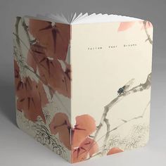 an open book with red flowers and leaves on the cover is sitting on a gray surface