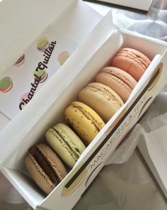 a box filled with different colored macaroons sitting on top of a white table