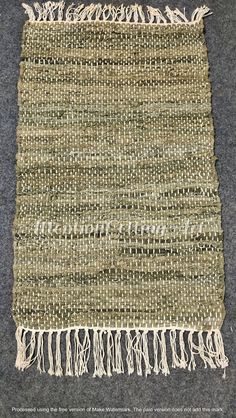 an old woven rug with fringes and beads on the bottom, sitting on a gray carpet