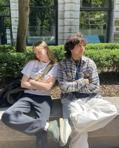 two people are sitting on a bench outside