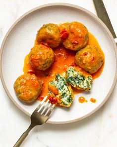 a white plate topped with meatballs covered in sauce