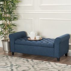 a gray bench with a cup on it and a potted plant in the corner