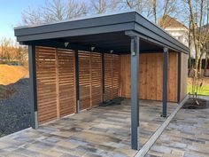 an outdoor carport with wooden slats on the sides and brick pavers flooring