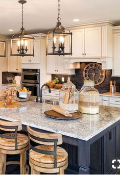 a large kitchen island with stools in front of it and lights hanging from the ceiling