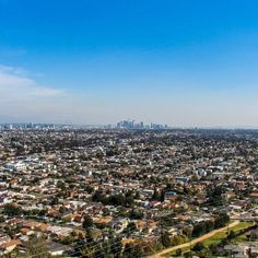 an aerial view of a city with lots of houses and trees in the foreground