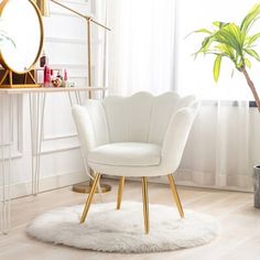 a white chair sitting on top of a wooden floor next to a potted plant