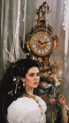 a woman in a white dress standing next to a clock