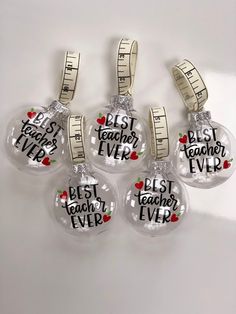 three clear glass ornaments with words on them and tape around the ornament that says, best teacher ever