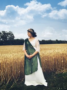 a woman standing in front of a wheat field wearing a green and white sari