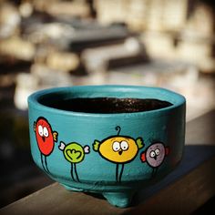 a potted plant with birds painted on it sitting on a window sill in front of a cityscape