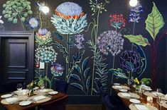 the dining room is decorated with colorful flowers and plants on the wall, along with place settings for four people