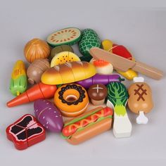 a pile of plastic toys including hot dogs, hamburgers and other foods on a white surface