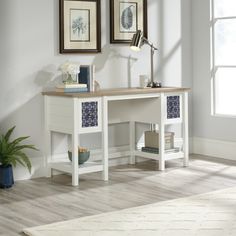 a white desk with two framed pictures on the wall and a chair in front of it