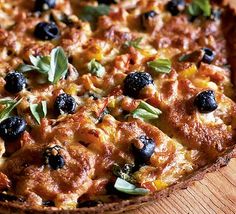 a pizza with olives, cheese and herbs