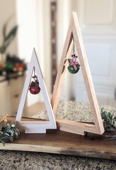 two triangle shaped wooden ornaments sitting on top of a counter next to a christmas tree