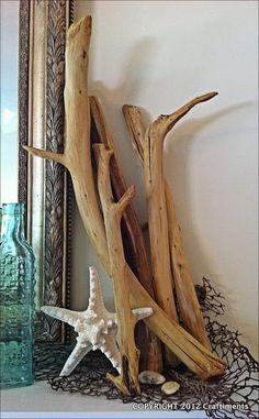 some driftwood and starfish on a shelf next to a glass vase with seashells in it