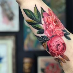 a woman's arm with flowers and leaves on it