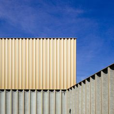 the side of a building that is made out of metal strips and has a blue sky in the background