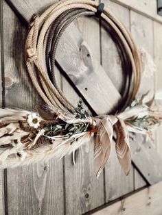 a wreath hanging on the side of a wooden wall with feathers and leaves attached to it