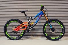 a colorful bike parked in front of a garage door with graffiti on the rims