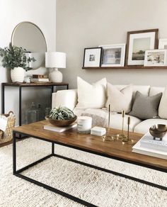 a living room with white couches and pictures on the wall above it, along with a coffee table