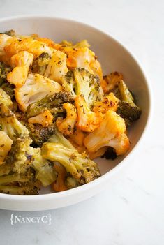 broccoli and cauliflower in a white bowl on a marble countertop