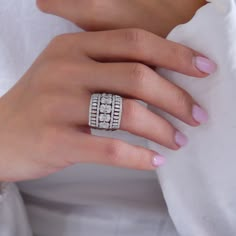 a woman's hand wearing a ring with three diamonds on the middle of it