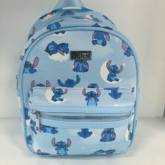 a blue backpack with an image of stitch and stitch characters on it, sitting on a white surface