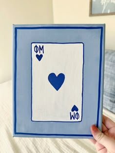 a hand holding up a blue and white playing card with two hearts on the front