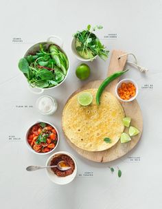 the ingredients for a mexican dish laid out on a cutting board, including tortillas and salsa