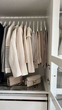 an organized closet with clothes and handbags hanging on the rail, including sweaters