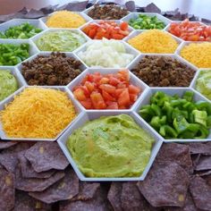 a table topped with bowls filled with different types of guacamole and chips