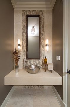 a bathroom with a sink, mirror and lights on the wall above it's counter