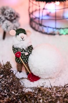 a stuffed animal is in the snow next to a fake snowman with a red rose