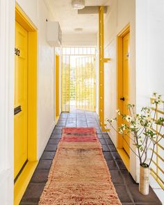 a hallway with yellow doors and rugs on the floor