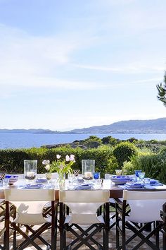 the table is set with plates and glasses on it, overlooking the ocean in the distance