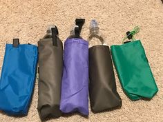 five water bottles lined up next to each other on the floor in front of a bag