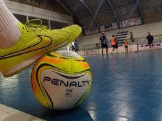 a soccer ball sitting on top of a blue floor in front of two people wearing orange socks