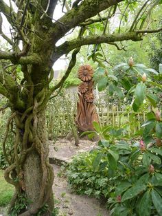 a wooden statue sitting in the middle of a lush green forest