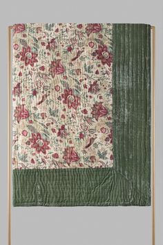 an old quilted wall hanging with flowers and leaves on the front, along with a green border