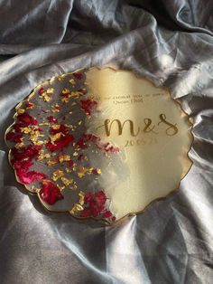 a plate with gold and red flowers on it sitting on a silver satin covered surface