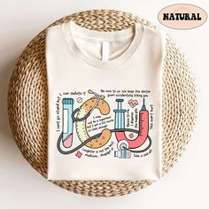 a white t - shirt with an illustration on the front and back of it, next to a wicker basket