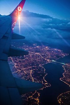 the wing of an airplane as it flies over a city at night with lights on