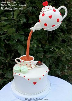 a cake with a teapot on top that is shaped like a cup and saucer