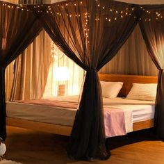 a canopy bed with lights hanging from it's sides and curtains on the side