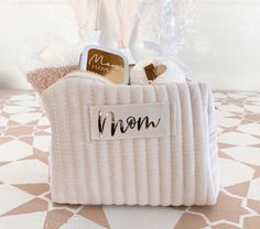 Curated with love and crafted for luxury, each tufted velvet pouch is personalized with "Mom" in Gold Foil and packed with items to pamper her. This Mother’s Day gift set is ready to send directly to mom from a daughter, son, or grandchildren.  Each COMPLETE mom gift set includes all the items listed below. What's Included:1 Ivory Tufted Velvet Makeup Bag1 Candle Tin – labeled with "Mom I Love You" in gold gold foil1 Bath Bomb - Gold with Gold Heart1 Beige Fuzzy SocksMaterial: VelvetSize of Bag: 8.5"L x 2.5"W x 5"H Candle Tin Labels, Mom Makeup, Velvet Makeup, Mom Texts, Makeup For Moms, Travel Toiletry Bag, Gold Bag, Spa Kit, Toiletry Bag Travel